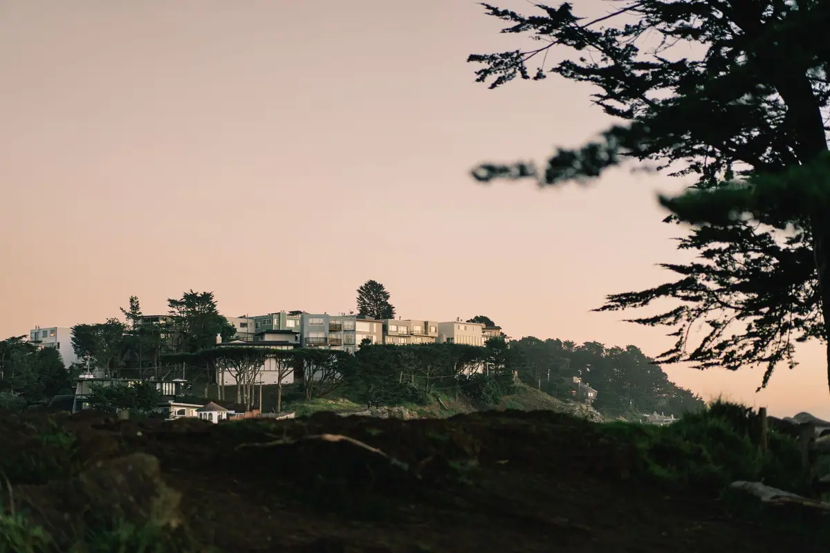 Hillside homes silhouetted against a warm sunset sky