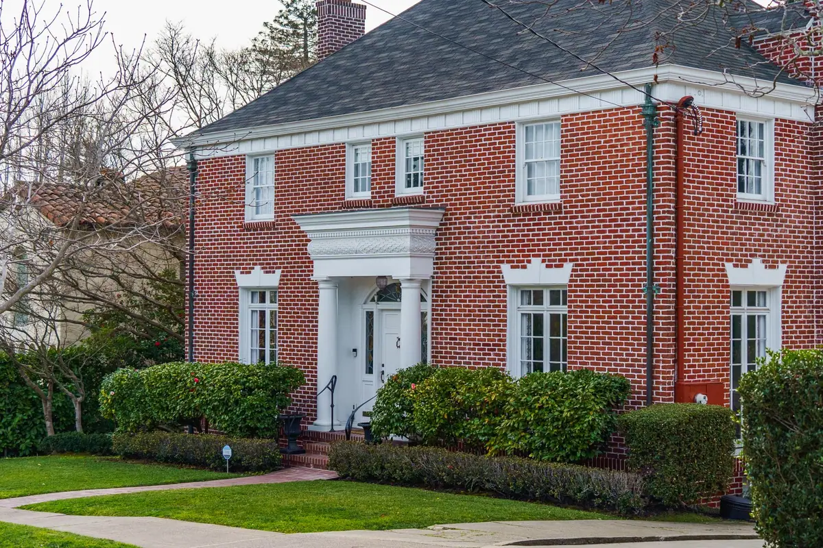 Traditional red brick two-storey home with white trim and a tidy front garden